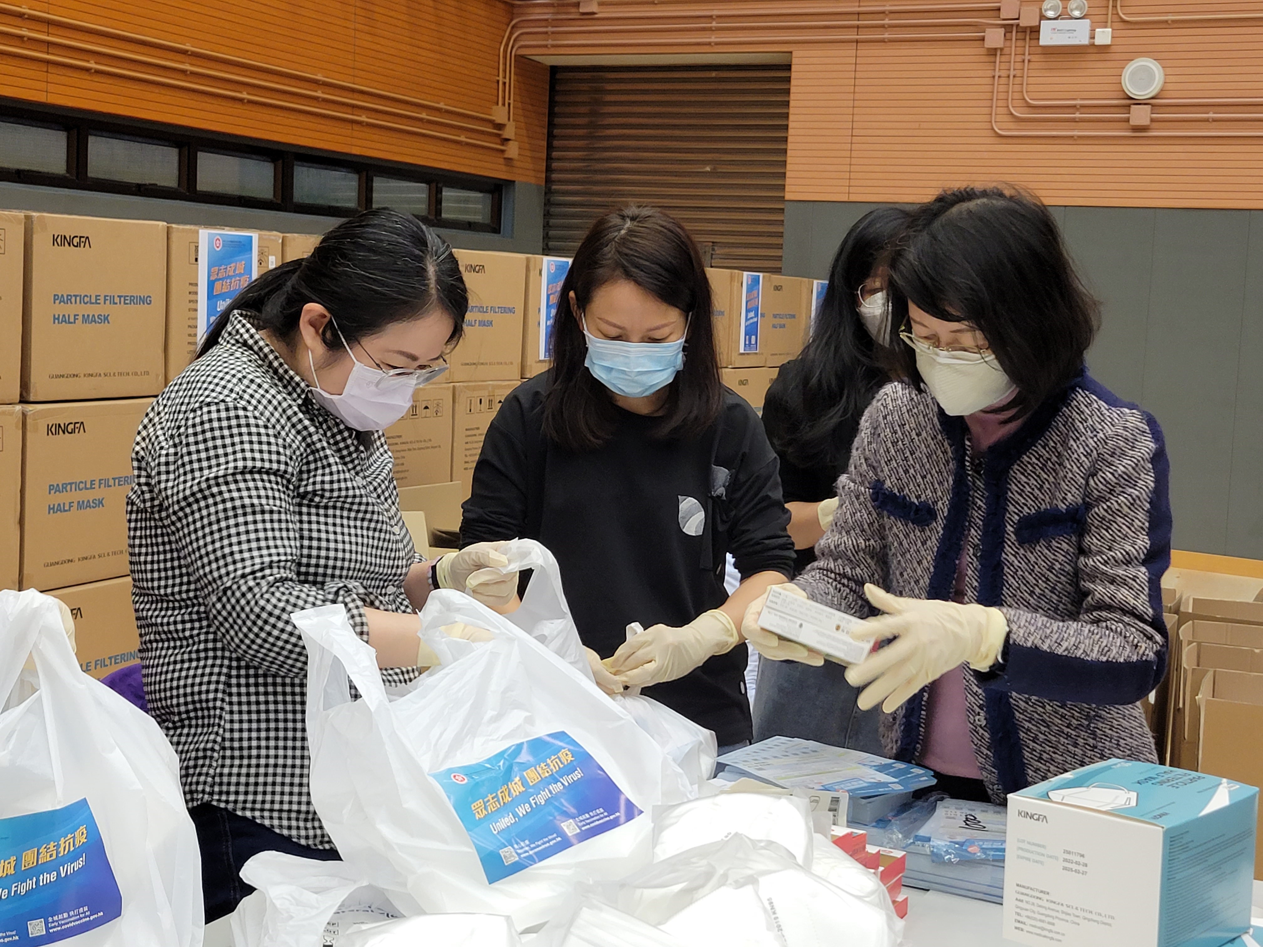 土 地 註 冊 處 處 長 譚 惠 儀 女 士 ， JP （右 一）與 同 事 一 起 進 行 防 疫 服 務 包 的 包 裝 工 作 。