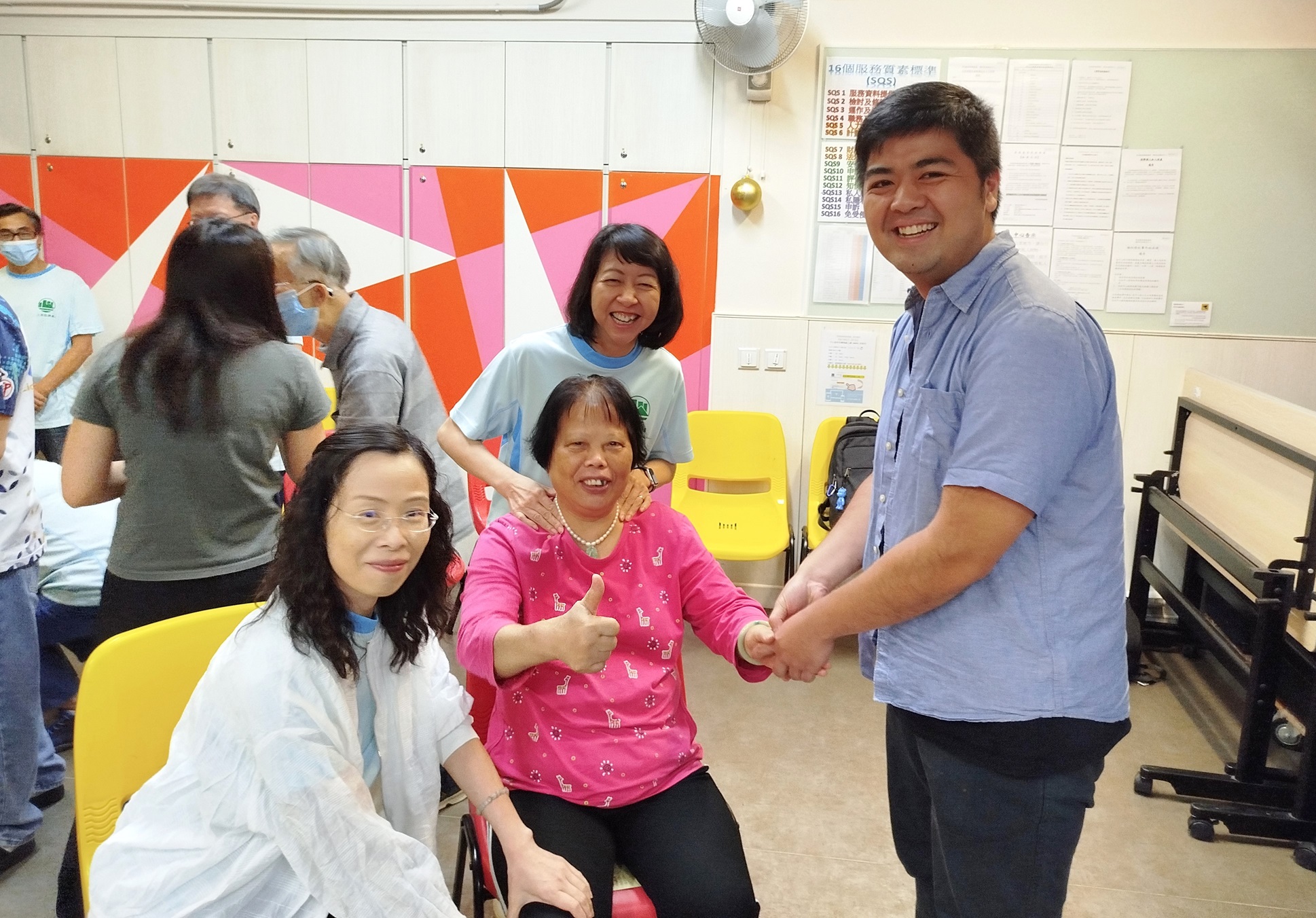 土 地 注 册 处 处 长 谭 惠 仪 女 士 （ 后 方 中 间 ） 率 领 部 门 义 工 队 为 居 于 顺 利 邨 的 长 者 及 其 照 顾 者 提 供 中 式 穴 位 按 摩 服 务